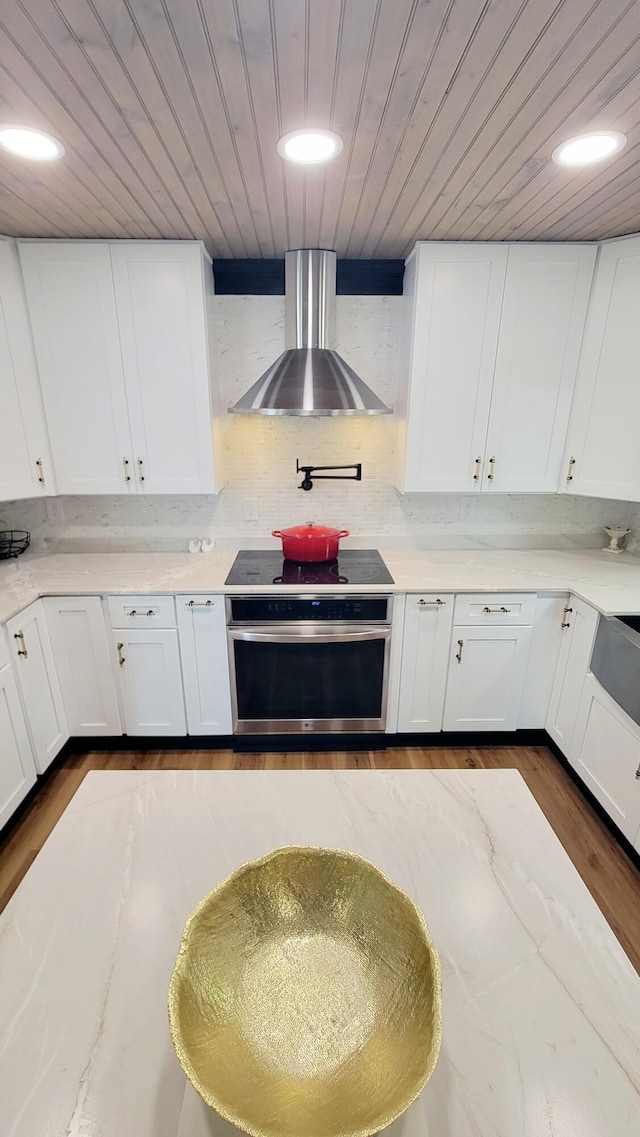 1131 Stringers Ridge Rd Unit 12H, Chattanooga, TN 37405 - kitchen with oven, wall chimney range hood, wood ceiling, white cabinets, and electric cooktop