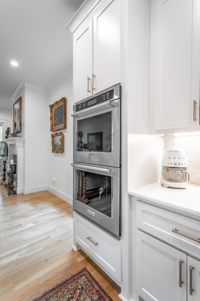 3117 Greenwich Ave, Chattanooga, TN 37415 - kitchen with stainless steel double oven, light wood-style flooring, white cabinets, crown molding, and light countertops