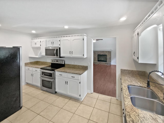 7110 Ridgestone Dr, Ooltewah, TN 37363 - kitchen featuring appliances with stainless steel finishes, white cabinetry, light tile patterned flooring, recessed lighting, and a fireplace