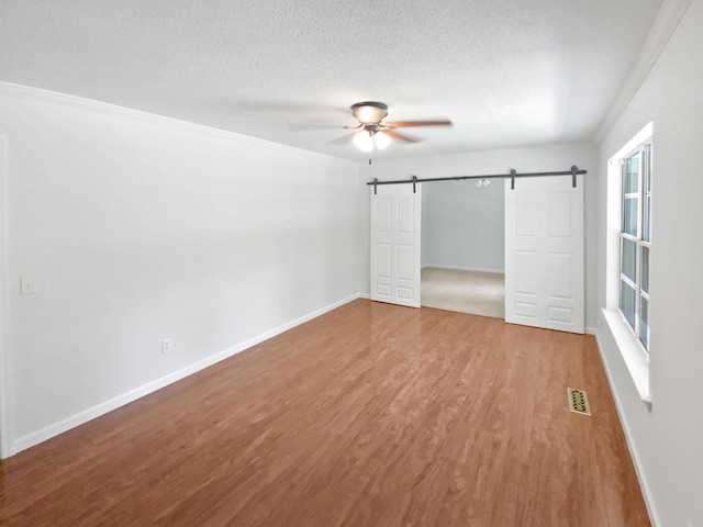 7110 Ridgestone Dr, Ooltewah, TN 37363 - unfurnished bedroom featuring a barn door, wood finished floors, a textured ceiling, and ceiling fan
