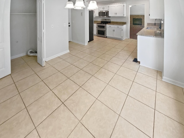 7110 Ridgestone Dr, Ooltewah, TN 37363 - kitchen with appliances with stainless steel finishes, light tile patterned flooring, white cabinets, and pendant lighting