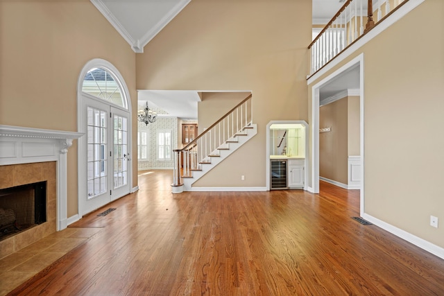 6401 Beacon Pointe Cir, Hixson, TN 37343 - unfurnished living room featuring wine cooler, crown molding, high vaulted ceiling, wood finished floors, and a tile fireplace