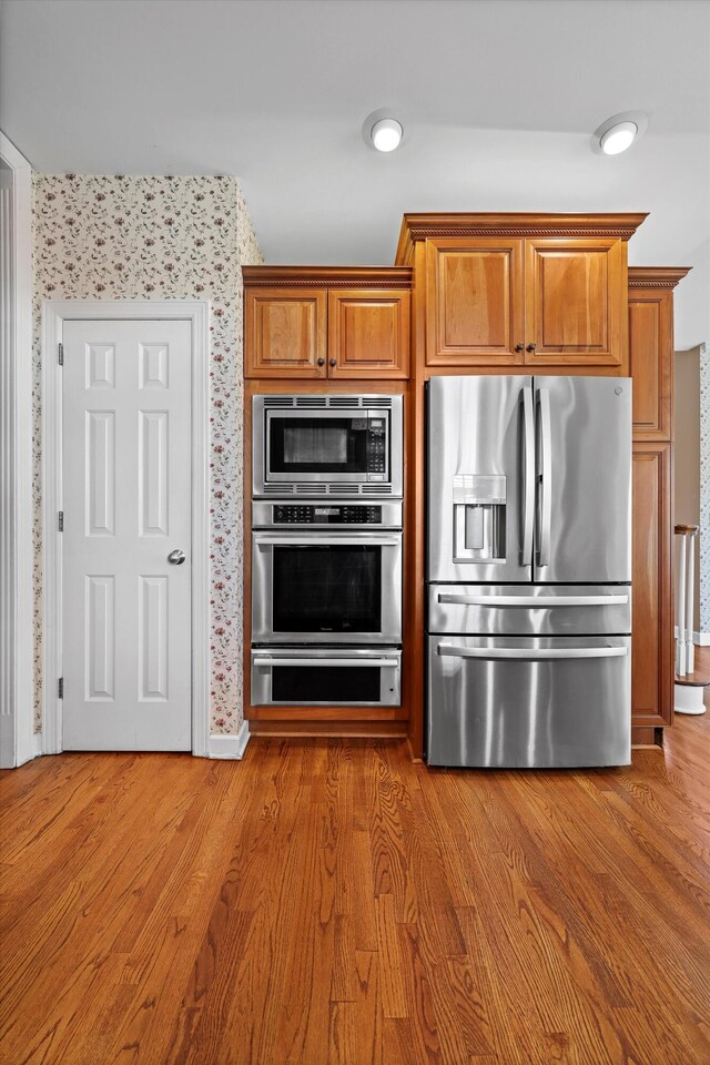 6401 Beacon Pointe Cir, Hixson, TN 37343 - kitchen with appliances with stainless steel finishes, wallpapered walls, brown cabinets, and wood finished floors