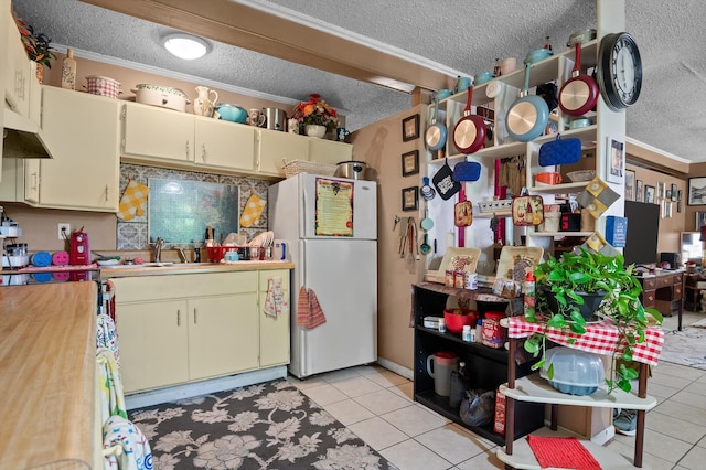 1618 E State Line Rd, Rossville, GA 30741 - kitchen with freestanding refrigerator, a textured ceiling, cream cabinetry, light tile patterned flooring, and crown molding