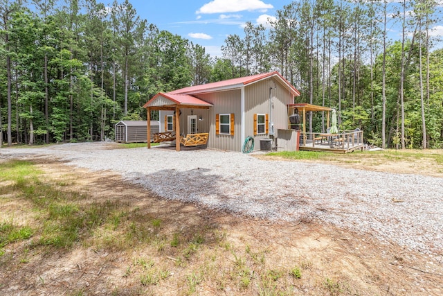1780 Wolf Haven Rd, Spencer, TN 38585 - view of front facade featuring a storage unit, a wooden deck, a metal roof, and a wooded view