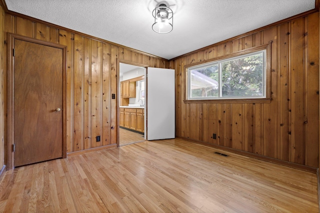 3712 Norma Dr, Chattanooga, TN 37412 - unfurnished bedroom with light wood finished floors, wooden walls, a textured ceiling, and connected bathroom