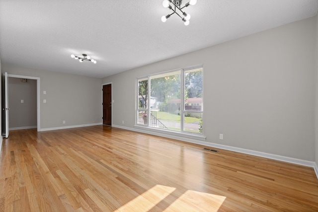 3712 Norma Dr, Chattanooga, TN 37412 - spare room featuring a textured ceiling, light wood-style flooring, and a chandelier