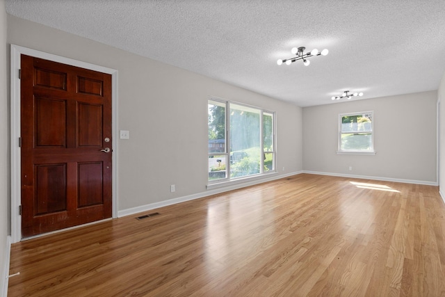 3712 Norma Dr, Chattanooga, TN 37412 - unfurnished room with a textured ceiling, light wood-type flooring, healthy amount of natural light, and a chandelier