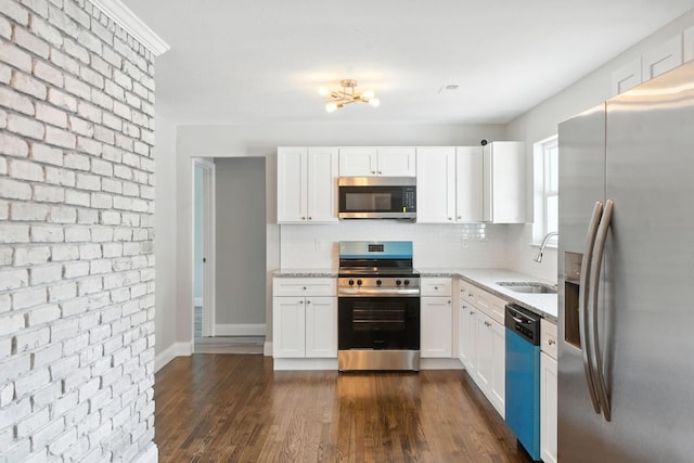 2207 Spencer Ave, Chattanooga, TN 37421 - kitchen featuring appliances with stainless steel finishes, backsplash, light stone counters, white cabinetry, and brick wall