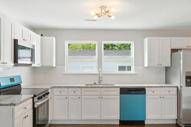 2207 Spencer Ave, Chattanooga, TN 37421 - kitchen with appliances with stainless steel finishes, white cabinetry, light stone countertops, and backsplash