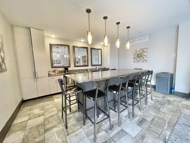1131 Stringers Ridge Rd Unit 4C, Chattanooga, TN 37405 - kitchen featuring white cabinetry, a breakfast bar area, a center island, light stone counters, and pendant lighting