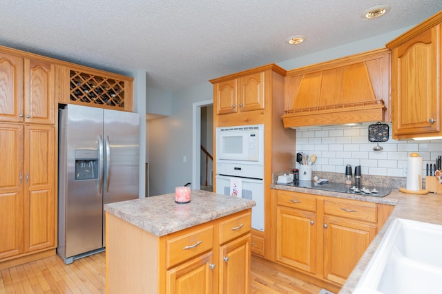 1510 Cannon Dr, Fort Oglethorpe, GA 30742 - kitchen featuring white appliances, premium range hood, light countertops, light wood-style floors, and a textured ceiling