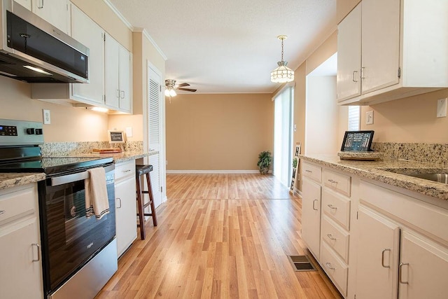 505 Heidi Cir, Chattanooga, TN 37415 - kitchen featuring appliances with stainless steel finishes, light wood finished floors, a ceiling fan, pendant lighting, and white cabinetry