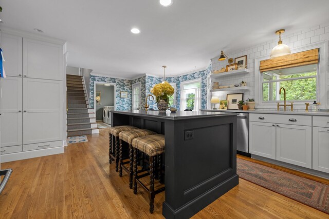 9420 Mountain Shadows Dr, Chattanooga, TN 37421 - kitchen featuring wallpapered walls, washer and dryer, a kitchen bar, white cabinets, and light wood-style floors