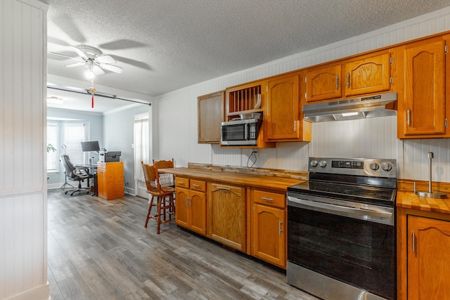 1602 Prater Rd, Chattanooga, TN 37412 - kitchen featuring appliances with stainless steel finishes, under cabinet range hood, wooden counters, crown molding, and wood finished floors