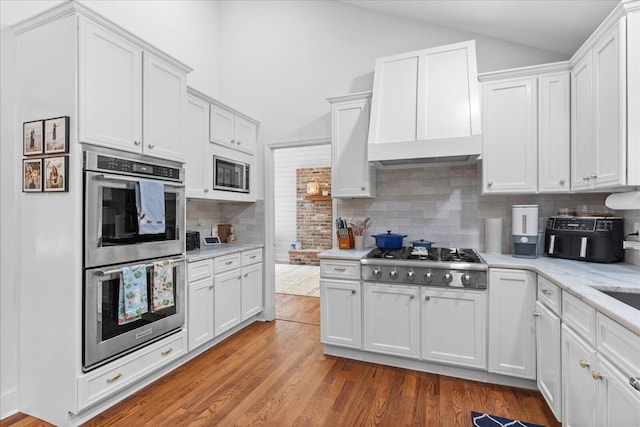110 Linden St, Lookout Mountain, TN 37350 - kitchen featuring appliances with stainless steel finishes, vaulted ceiling, white cabinetry, wood finished floors, and backsplash