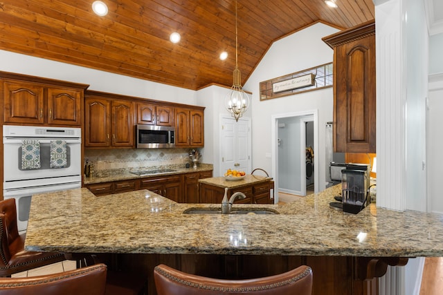 4101 Finch Ln, Chattanooga, TN 37419 - kitchen with white double oven, stainless steel microwave, wood ceiling, light stone counters, and a kitchen bar