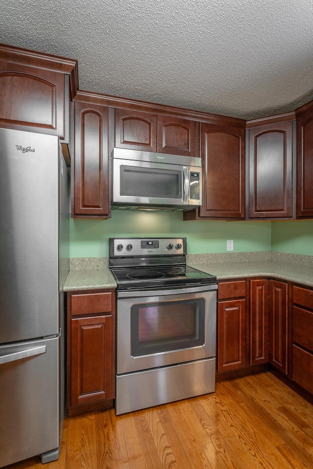 8217 Rolling Stone Ln, Ooltewah, TN 37363 - kitchen featuring stainless steel appliances, a textured ceiling, light countertops, and light wood-style flooring