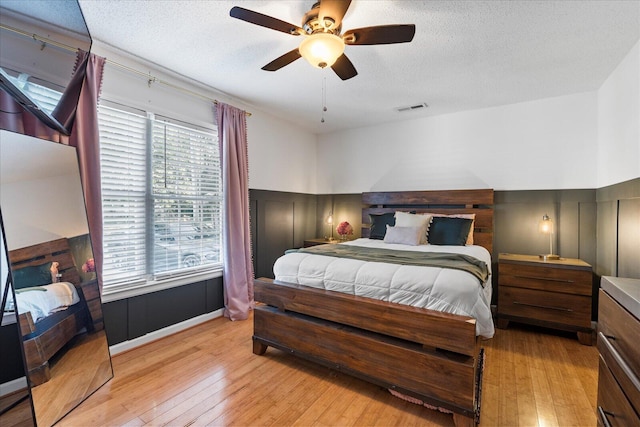 3305 Redding Rd, Chattanooga, TN 37415 - bedroom featuring light wood-style flooring, a decorative wall, wainscoting, a textured ceiling, and ceiling fan