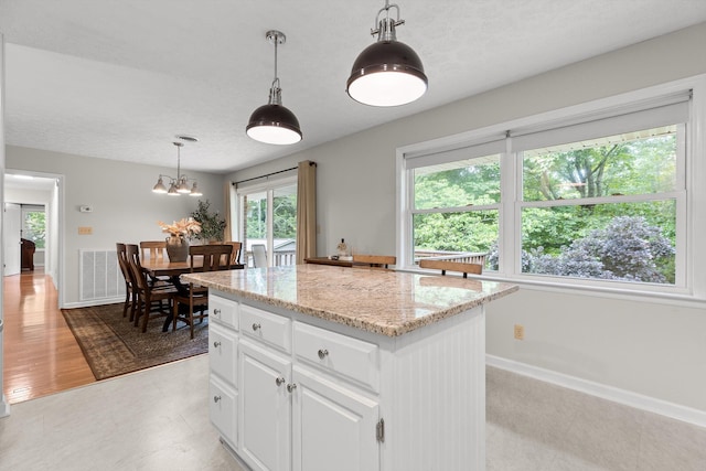 28 Lynn Rd, Signal Mountain, TN 37377 - kitchen featuring light stone counters, white cabinets, decorative light fixtures, a center island, and a textured ceiling