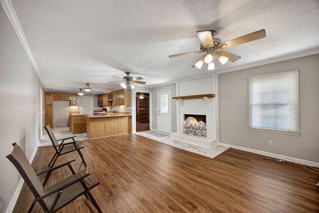 15 Moon Beam Cir, Rock Spring, GA 30739 - unfurnished living room with crown molding, a textured ceiling, a ceiling fan, light wood-style flooring, and a brick fireplace