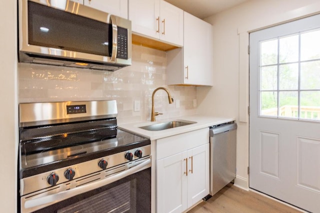 318 Yates Springs Rd, Ringgold, GA 30736 - kitchen featuring stainless steel appliances, light countertops, decorative backsplash, white cabinets, and light wood-style flooring