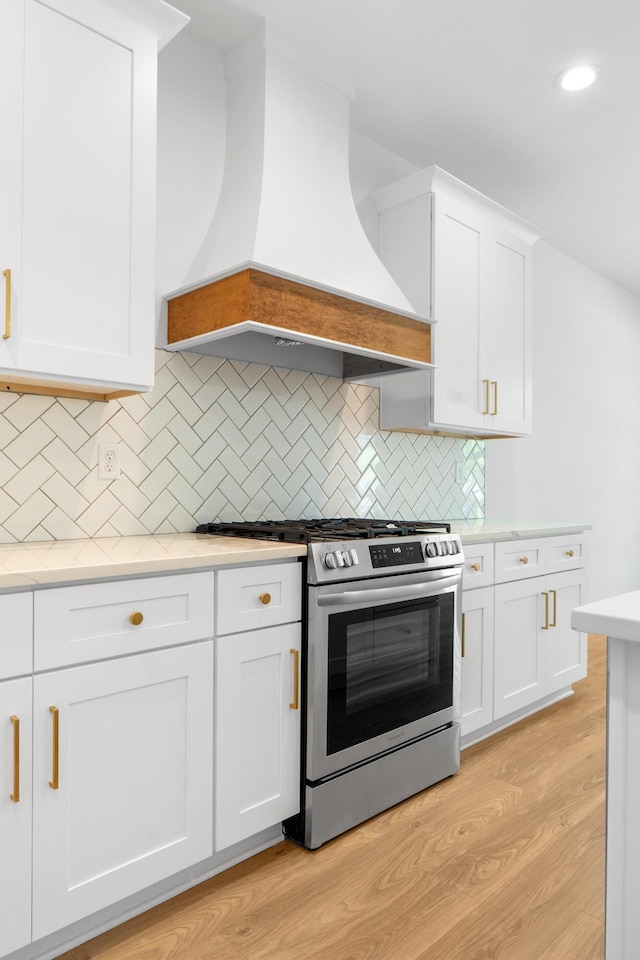 6821 Lakeshore Dr, Chattanooga, TN 37416 - kitchen with stainless steel range with gas stovetop, custom exhaust hood, light countertops, white cabinetry, and tasteful backsplash