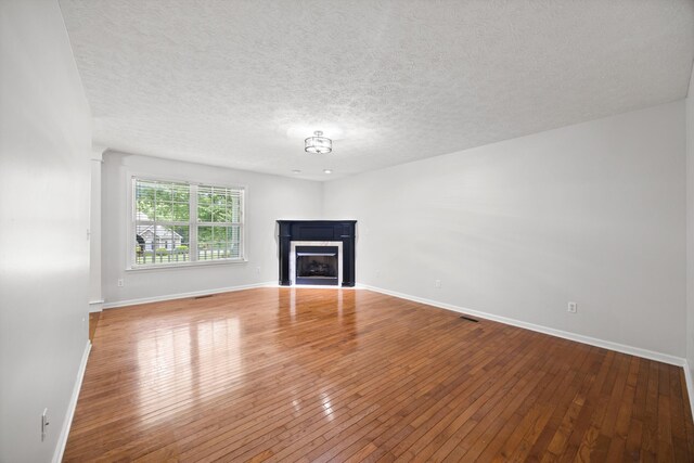 75 Sequoyah Trl, Ringgold, GA 30736 - unfurnished living room featuring wood-type flooring, a fireplace with flush hearth, and a textured ceiling