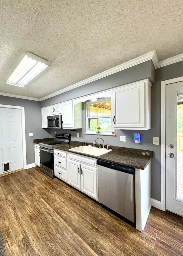 1828 Saunders Rd, Ringgold, GA 30736 - kitchen with stainless steel appliances, a textured ceiling, dark countertops, ornamental molding, and white cabinetry