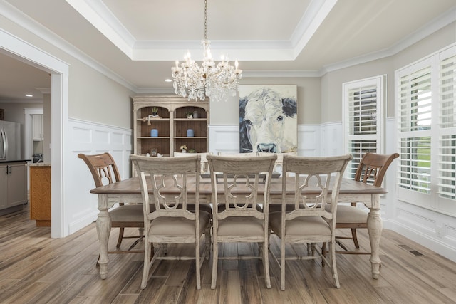 305 River Pointe Cir NE, Charleston, TN 37310 - dining space featuring a decorative wall, a chandelier, light wood-style flooring, a raised ceiling, and wainscoting