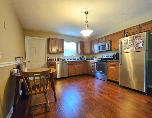 407 W 3rd St, Jasper, TN 37347 - kitchen featuring stainless steel appliances, dark wood-style flooring, hanging light fixtures, a textured ceiling, and brown cabinetry