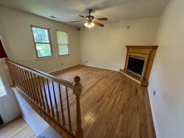 311 Branch Dr, Hixson, TN 37343 - unfurnished living room featuring wood-type flooring, a fireplace with raised hearth, a ceiling fan, and a textured ceiling