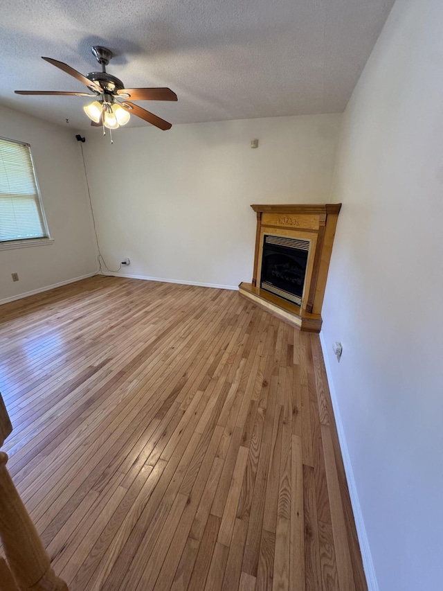 311 Branch Dr, Hixson, TN 37343 - unfurnished living room featuring light wood finished floors, a textured ceiling, a ceiling fan, and a fireplace with raised hearth