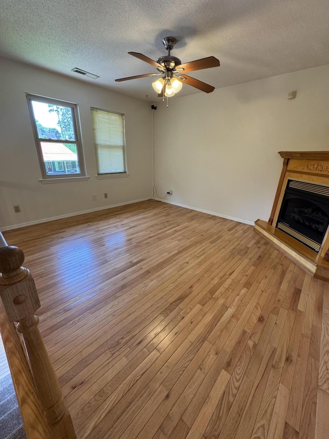311 Branch Dr, Hixson, TN 37343 - unfurnished living room featuring light wood finished floors, a textured ceiling, ceiling fan, and a fireplace with raised hearth