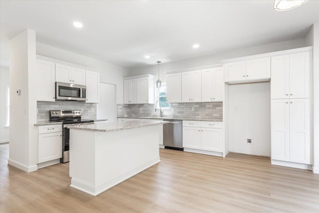 845 James Ave, Chattanooga, TN 37421 - kitchen with appliances with stainless steel finishes, tasteful backsplash, light wood-type flooring, white cabinets, and a kitchen island