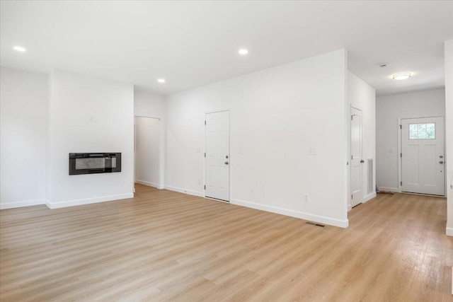845 James Ave, Chattanooga, TN 37421 - unfurnished living room featuring heating unit, light wood-style floors, a glass covered fireplace, and recessed lighting