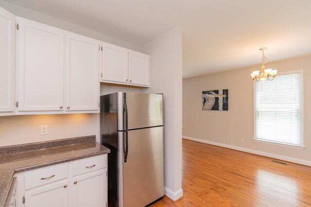 1106 Flynn St, Chattanooga, TN 37403 - kitchen with freestanding refrigerator, white cabinets, light wood-type flooring, and a chandelier