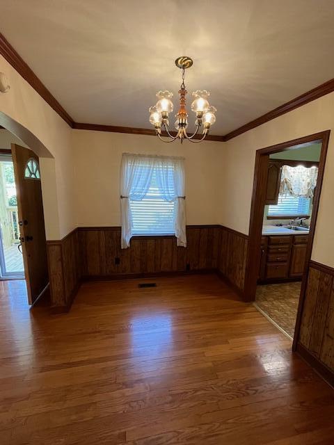 4630 Happy Valley Rd, Flintstone, GA 30725 - unfurnished dining area featuring wainscoting, wood finished floors, arched walkways, wooden walls, and a chandelier