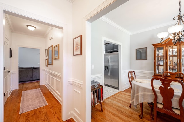 8502 Kennerly Ct, Ooltewah, TN 37363 - dining room featuring light wood finished floors, a chandelier, ornamental molding, a decorative wall, and wainscoting