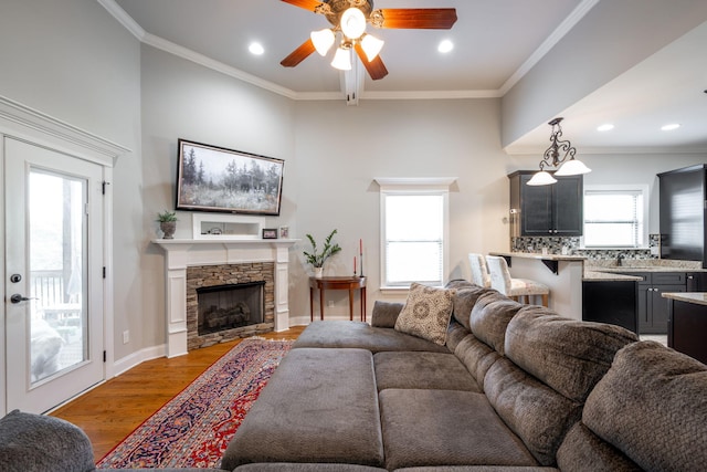 8502 Kennerly Ct, Ooltewah, TN 37363 - living room featuring a ceiling fan, light wood-style flooring, recessed lighting, a stone fireplace, and crown molding
