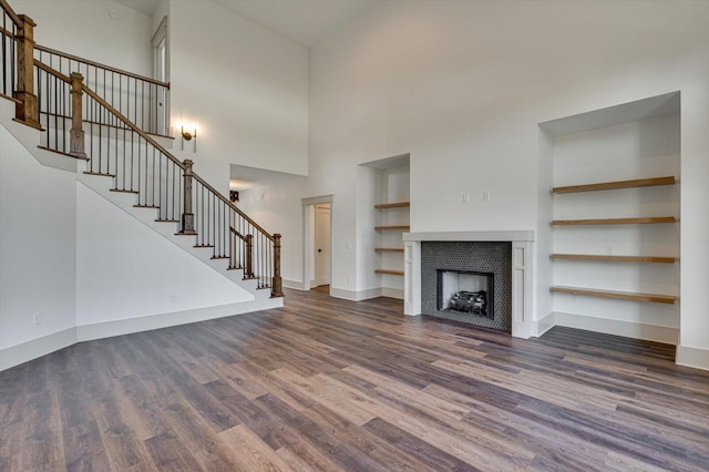 7104 Paxton Cir, Hixson, TN 37343 - unfurnished living room featuring dark wood-type flooring, stairway, built in features, a high ceiling, and a fireplace