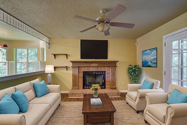 9028 Warbler Ln, Chattanooga, TN 37421 - living room featuring wood finished floors, a ceiling fan, a fireplace, and a textured ceiling