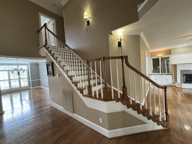 6419 Camdendown Ln, Hixson, TN 37343 - stairway with a chandelier, wood finished floors, a fireplace, ornamental molding, and a towering ceiling