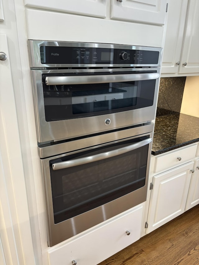 6419 Camdendown Ln, Hixson, TN 37343 - kitchen featuring stainless steel double oven, white cabinets, backsplash, dark wood finished floors, and dark stone countertops