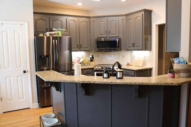 7354 Kayla Beth Ct, Ooltewah, TN 37363 - kitchen featuring appliances with stainless steel finishes, gray cabinetry, a breakfast bar, light stone counters, and recessed lighting
