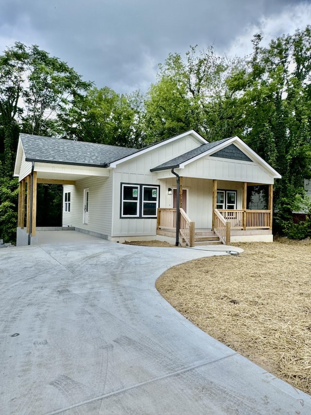 612 Shannon Ave, Chattanooga, TN 37411 - view of front facade featuring driveway, board and batten siding, covered porch, an attached carport, and a shingled roof