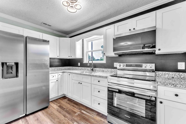 3010 Georgetown Dr NW, Cleveland, TN 37312 - kitchen featuring stainless steel appliances, a textured ceiling, crown molding, white cabinets, and wood finished floors