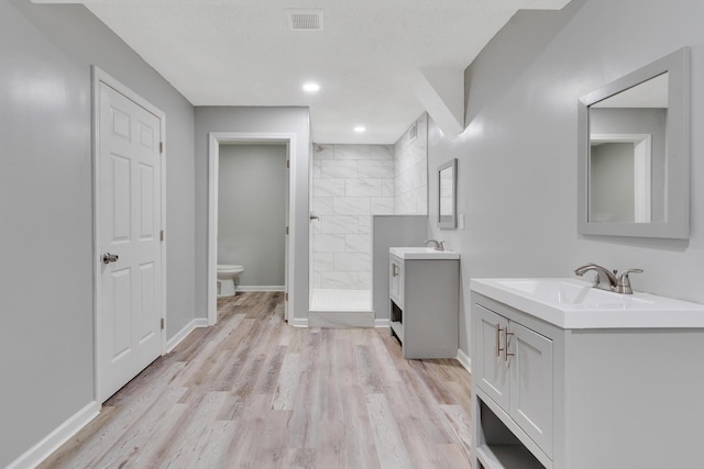 4212 Rogers Rd, Chattanooga, TN 37411 - bathroom with a walk in shower, two vanities, wood finished floors, and recessed lighting