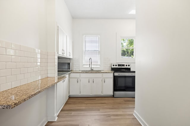 1306 Bailey Ave, Chattanooga, TN 37404 - kitchen with appliances with stainless steel finishes, light wood-style floors, tasteful backsplash, white cabinets, and light stone counters