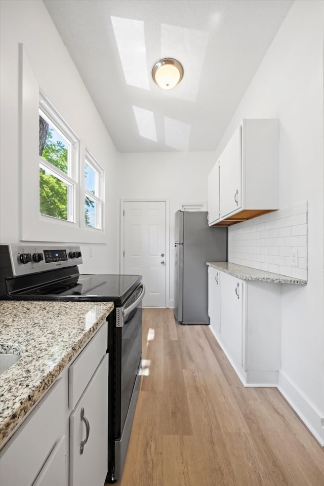 1306 Bailey Ave, Chattanooga, TN 37404 - kitchen with stainless steel appliances, light wood-style floors, a skylight, white cabinets, and light stone counters
